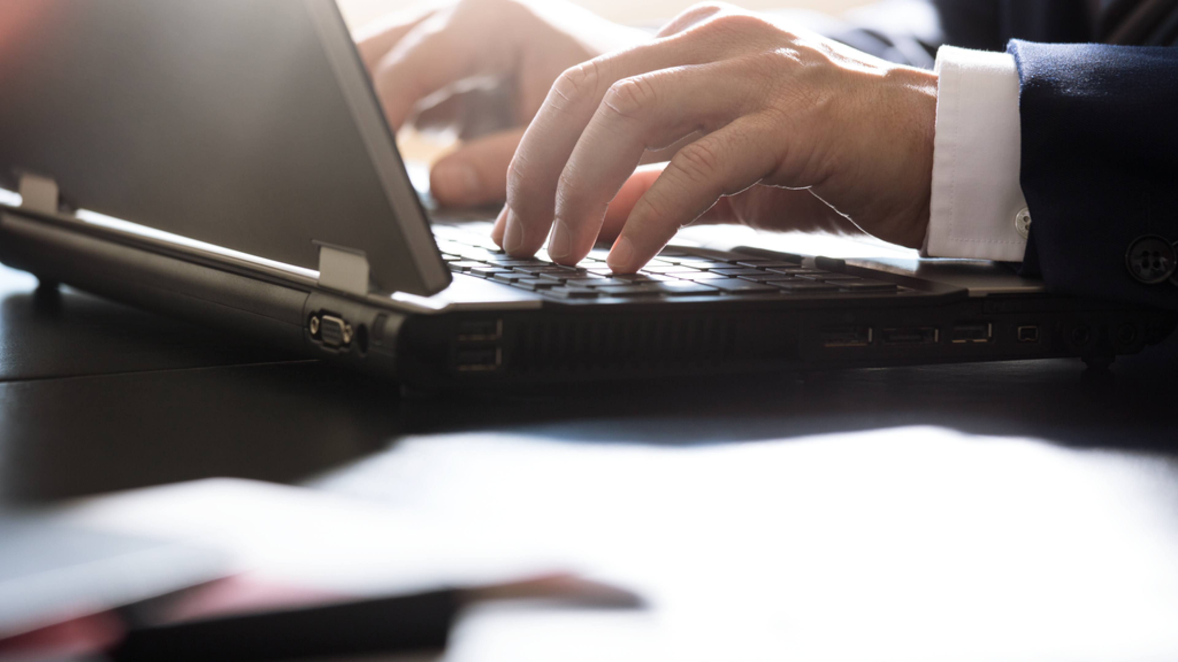 Close up image of a man's hands typing on a laptop 